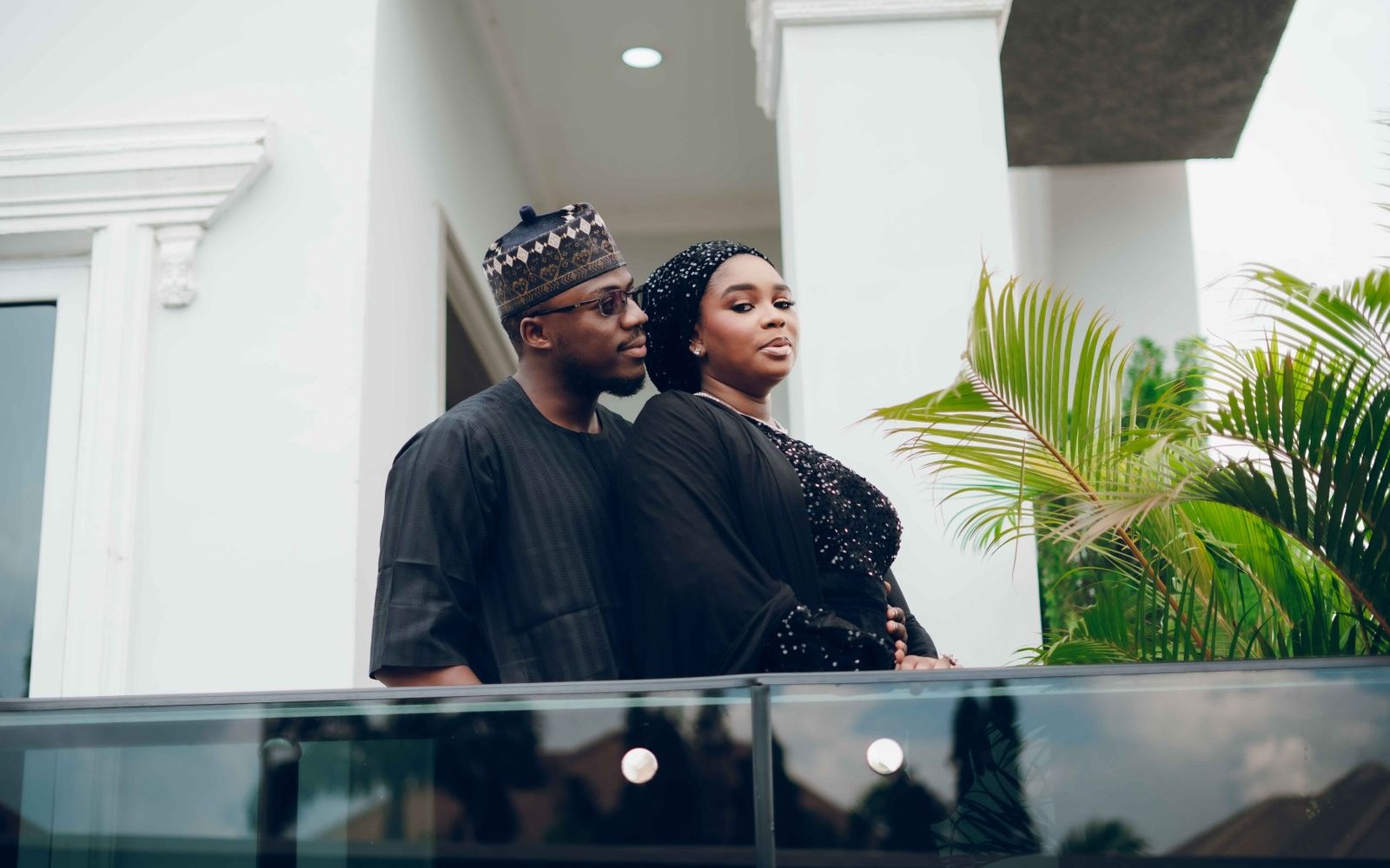 A Nigerian couple in traditional attire standing together on a balcony